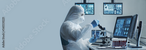 Tableau sur toile Scientist in protection suit and masks working in research lab using laboratory equipment: microscopes, test tubes