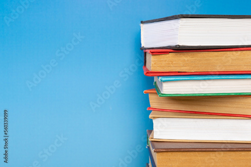 Stack of books in the colored cover lay on blue backround. Education learning concept