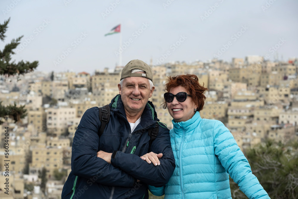 a man and a woman against the background of the residential areas of Amman and against the background of the flag of the country