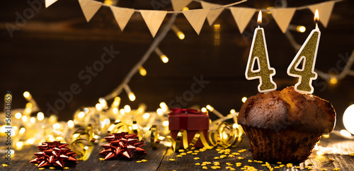 Number 44 golden festive burning candles in a cake, wooden holiday background. forty four years from the date of birth. the concept of celebrating a birthday, anniversary, holiday. Banner. photo