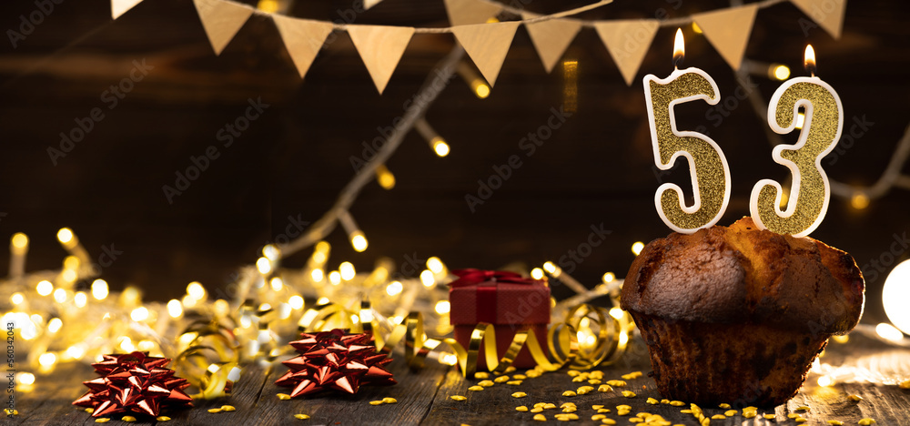 Number 53 golden festive burning candles in a cake, wooden holiday background. fifty-three years since the birth. the concept of celebrating a birthday, anniversary, holiday. Banner.