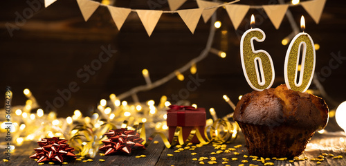 Number 60 golden festive burning candles in a cake, wooden holiday background. sixty years of birth. the concept of celebrating a birthday, anniversary, holiday. Banner. photo