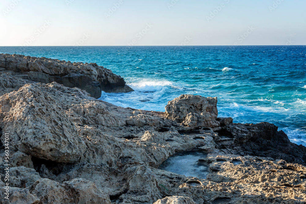Rocky shore of the turquoise sea against the background of a clear blue sky. Beautiful scenery and relaxation.