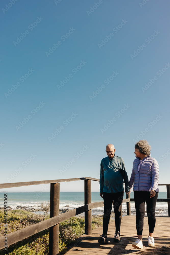 Retired senior couple taking a walk along a bridge at the beach Retired senior couple taking a walk along a bridge at the beach
