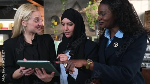 three elegant women of different ethnicity using tablet and working together.