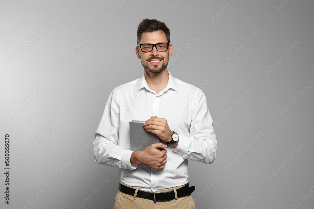 Happy teacher with book against beige background Happy teacher with book against beige background