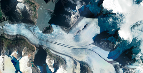 aerial view of glacier between rocky and snowy mountains
