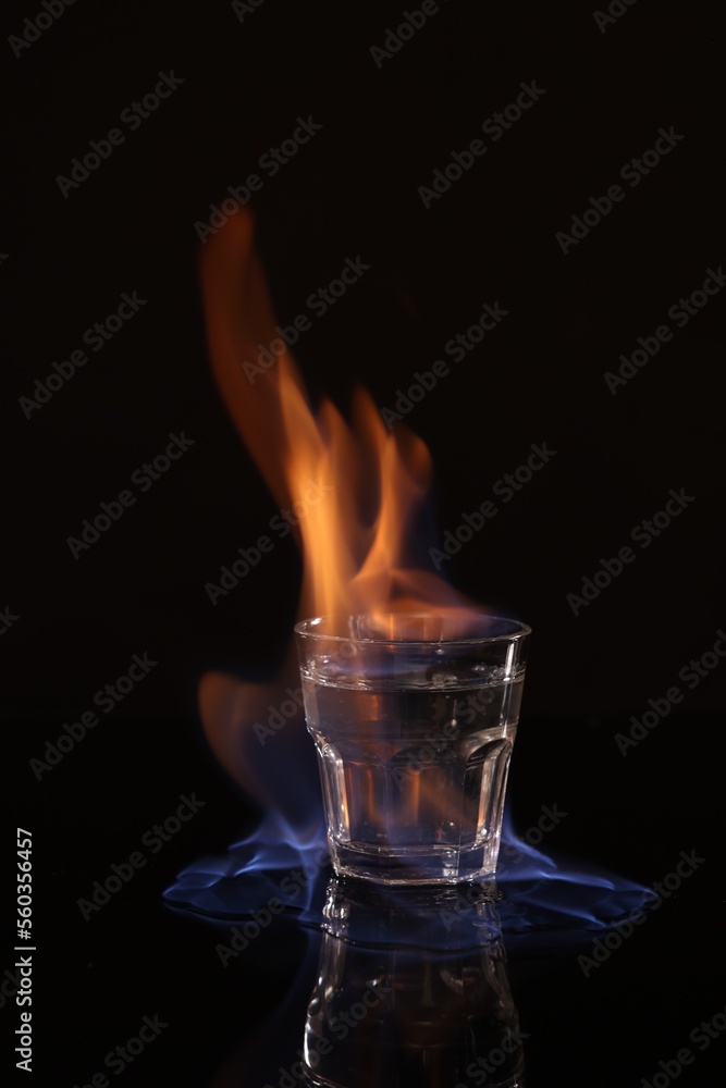 Flaming vodka in shot glass on black background Flaming vodka in shot glass on black background