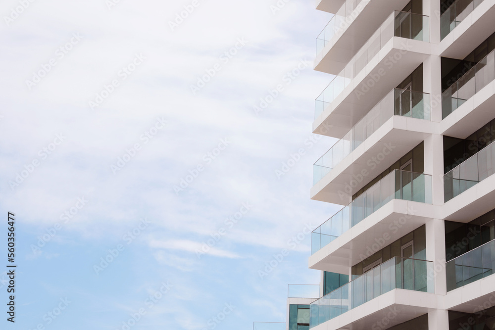 Exterior of residential building with balconies against blue sky, low angle view. Space for text Exterior of residential building with balconies against blue sky, low angle view. Space for text