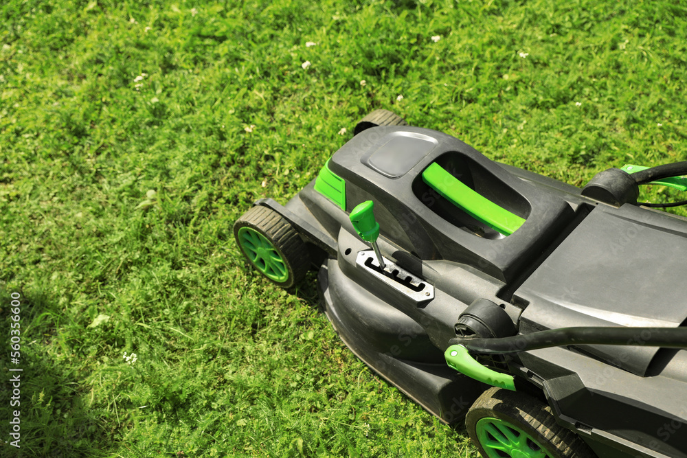 Lawn mower on green grass in garden. Space for text Lawn mower on green grass in garden. Space for text