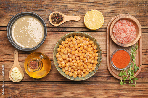 Delicious chickpeas and different products on wooden table, flat lay. Hummus ingredient