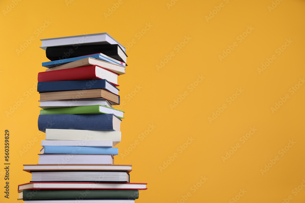 Stack of hardcover books on orange background. Space for text Stack of hardcover books on orange background. Space for text