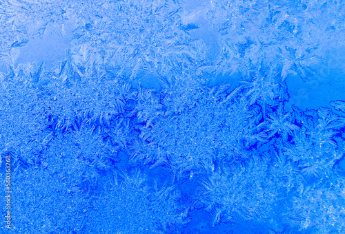 Frost patterns on a window in winter day (blue background)
