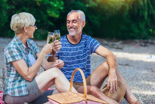 Cute senior couple enjoying picnic time on the riverside.