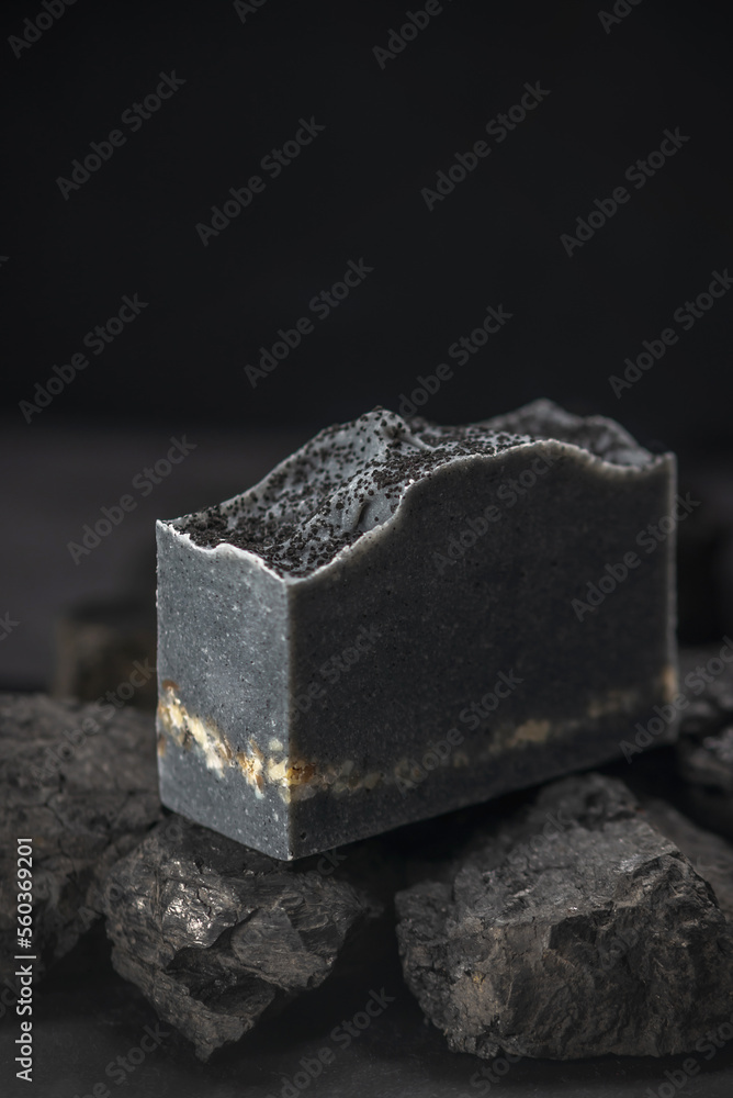 Piece of natural charcoal soap on real coals on a black background. Concept of making and using organic eco soap and cosmetics Piece of natural charcoal soap on real coals on a black background. Concept of making and using organic eco soap and cosmetics