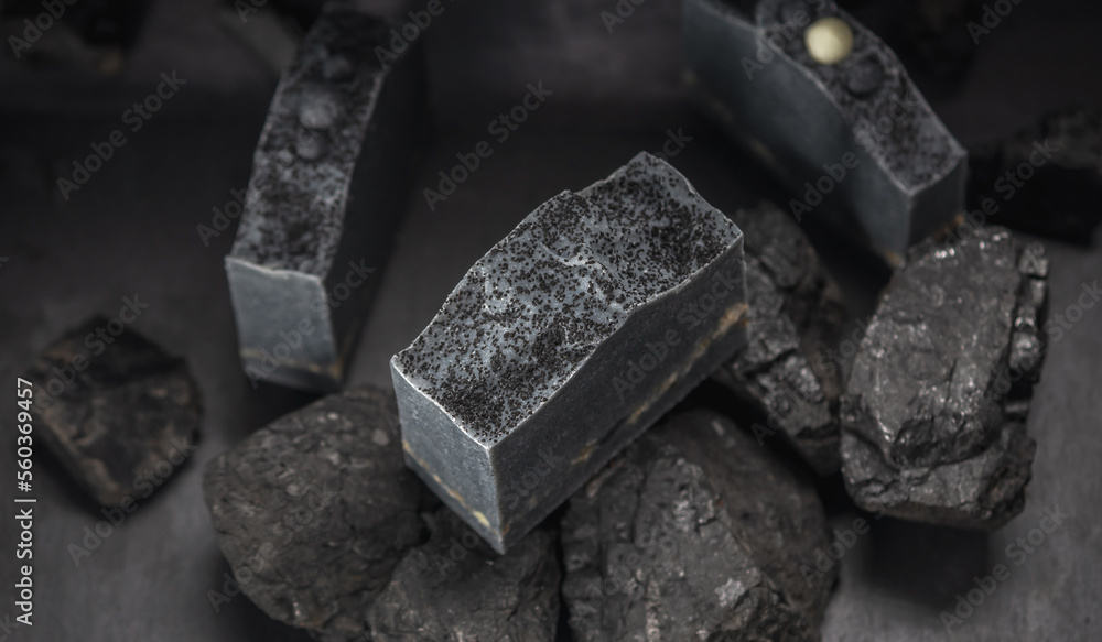 Natural charcoal soap on real coals on a dark background. Concept of making and using organic eco soap and cosmetics Natural charcoal soap on real coals on a dark background. Concept of making and using organic eco soap and cosmetics