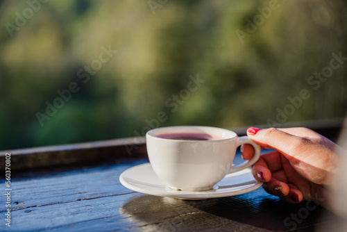 Close-up shot of a cup of tea in a woman's hand. Young female tourist drinking hot drink from a cup and enjoying the scenery in the mountains.