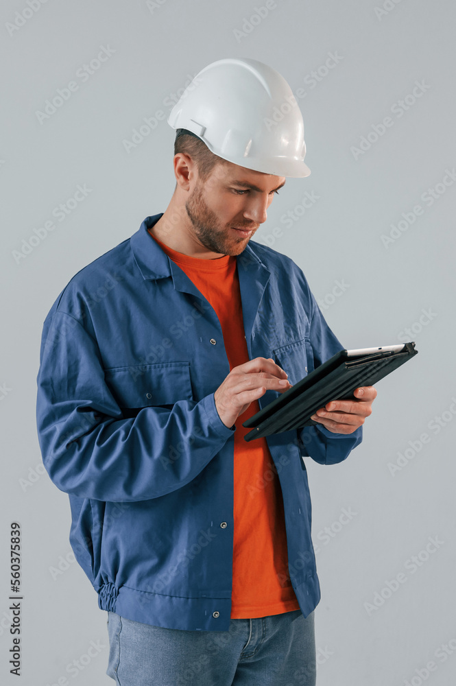 Construction worker in hard hat is with tablet. Handsome man is in the studio against white background Construction worker in hard hat is with tablet. Handsome man is in the studio against white background