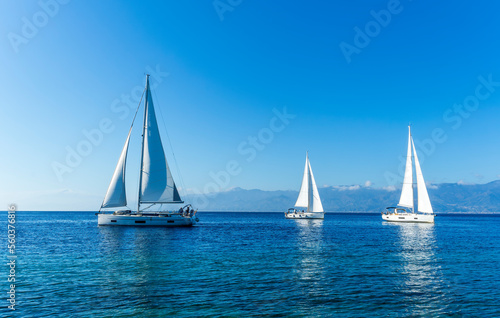 sailing yacht boats with white sails in blue sea , seascape of beautiful ships in sea gulf with mountain coast on background