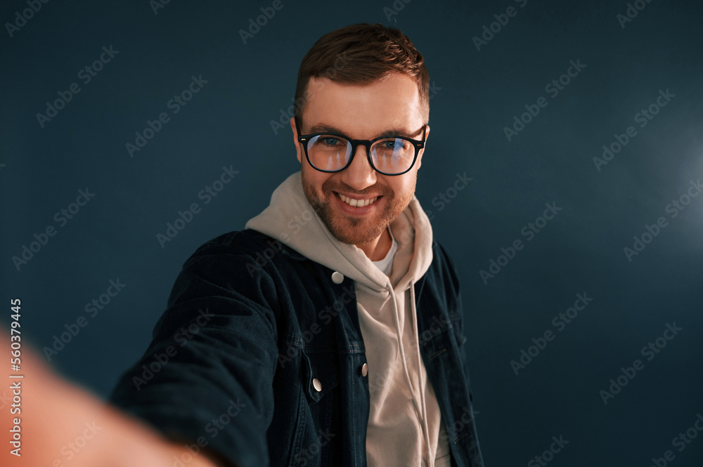Making selfie. Handsome man is in the studio against blue background Making selfie. Handsome man is in the studio against blue background
