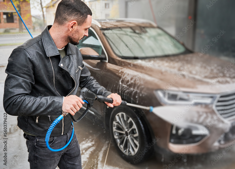 Man cleaning car by water from high pressure water gun. Man cleaning car by water from high pressure water gun.