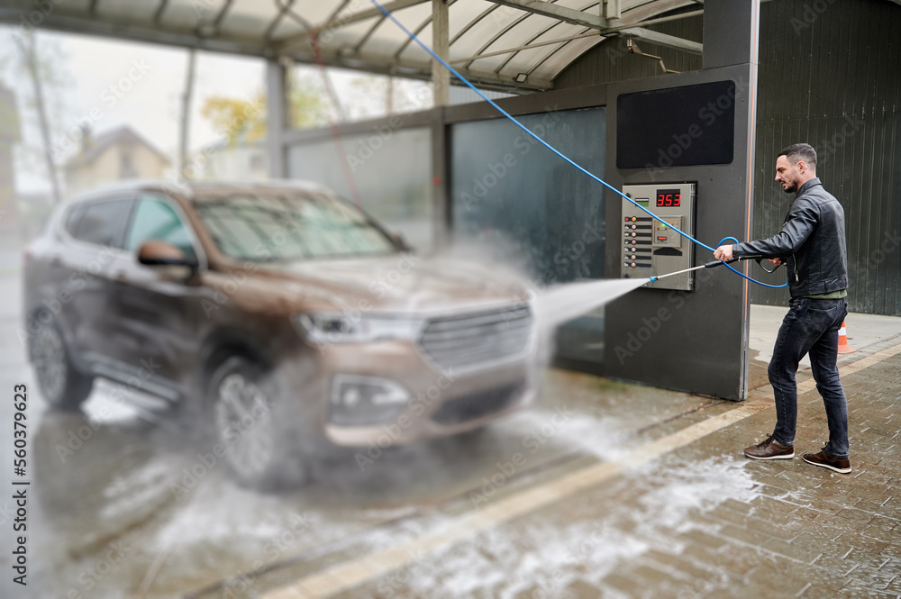 Young man washing car on carwash station outdoor Young man washing car on carwash station outdoor