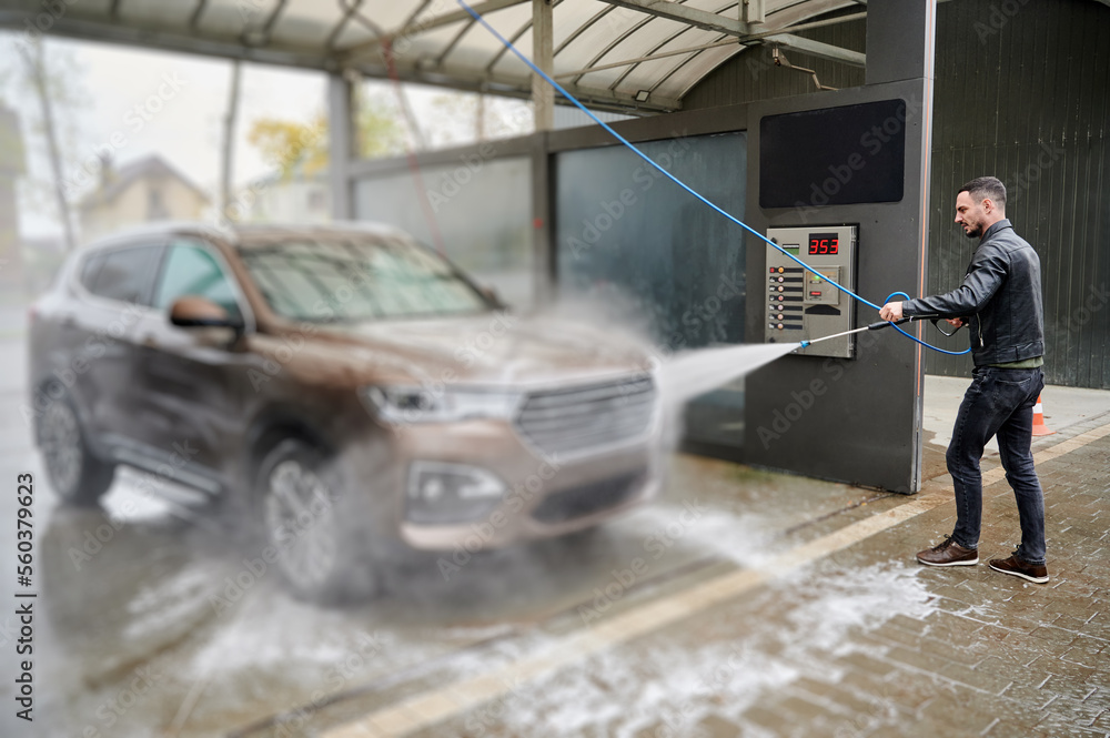 Young man washing car on carwash station outdoor