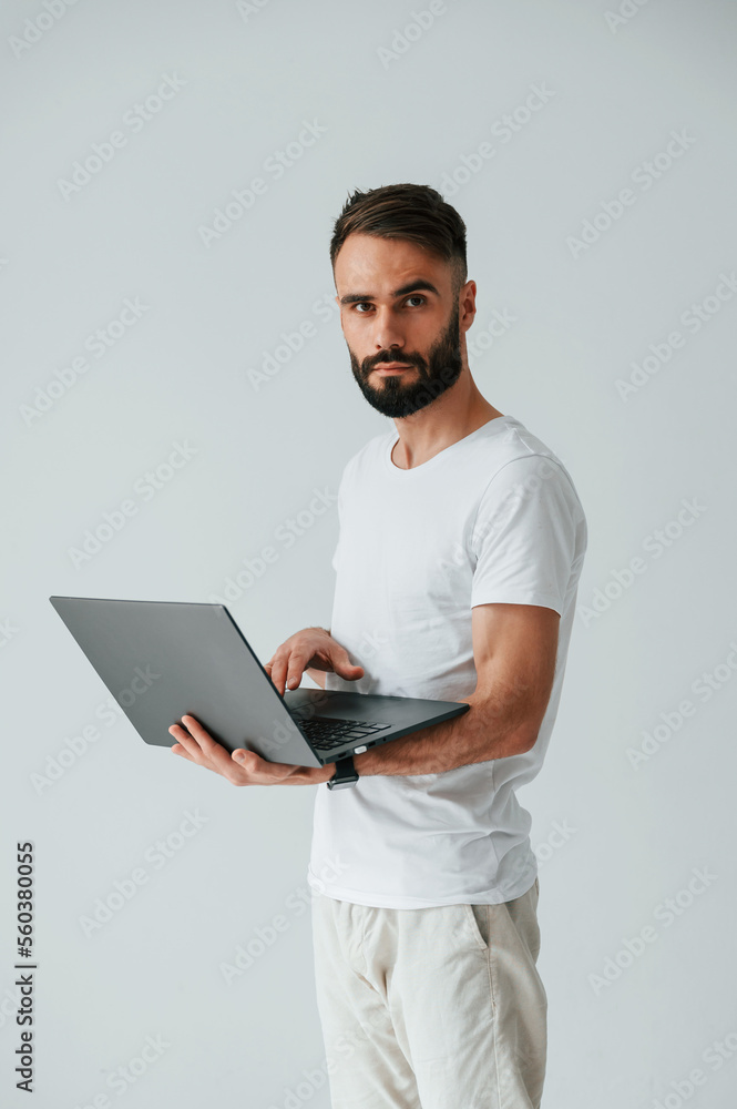 Silver colored laptop in hands. Handsome man is in the studio against white background Silver colored laptop in hands. Handsome man is in the studio against white background