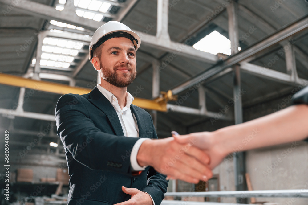 Handshake with partner. Manager in black formal wear at the factory Handshake with partner. Manager in black formal wear at the factory
