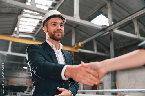 Handshake with partner. Manager in black formal wear at the factory