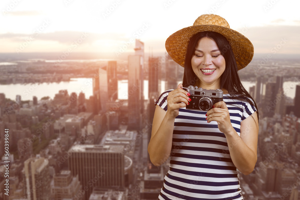 Young tourist asian woman with vintage photo camera. Cityscape with evening sunset on background.