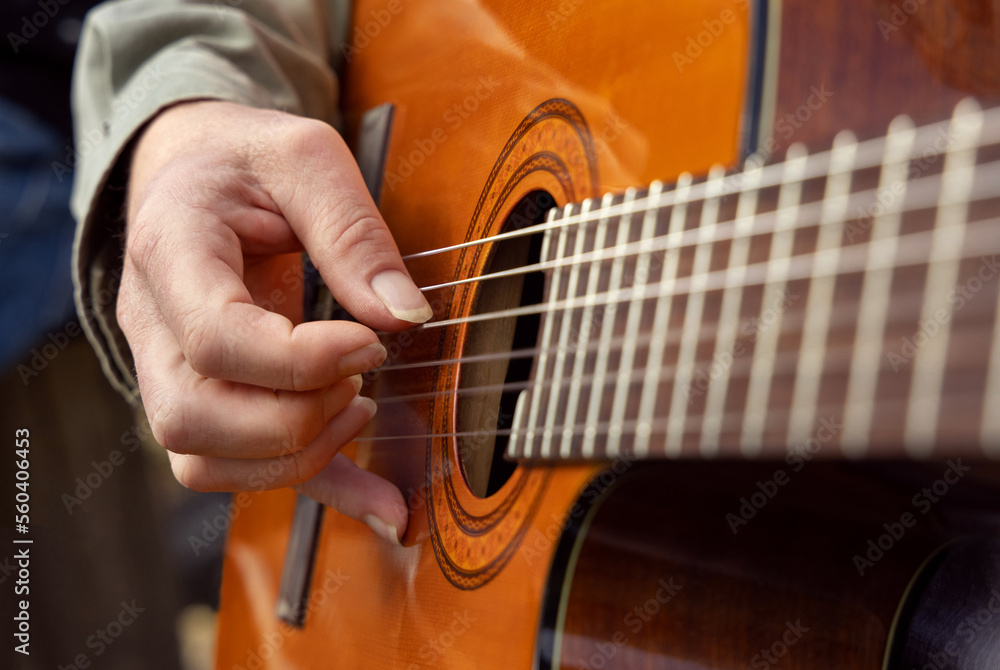 Fototapeta premium Male hands playing acoustic guitar, close up. Teacher is giving guitar lesson
