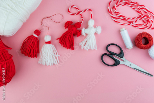 Woman making handmade traditional martisor, from red and white strings with tassel. Symbol of holiday 1 March, Martenitsa, Baba Marta, beginning of spring in Romania, Bulgaria, Moldova photo