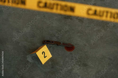 Crime scene. Top view of knife clue with blood. Police causion tape photo