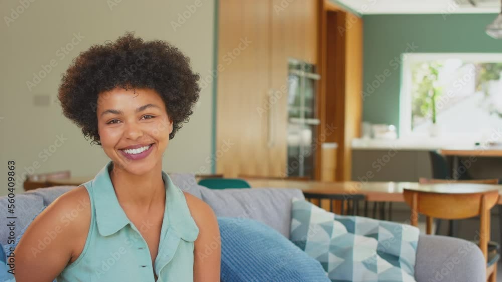 Portrait of woman sitting on sofa in stylish lounge dining room smiling and laughing at camera - shot in slow motion Portrait of woman sitting on sofa in stylish lounge dining room smiling and laughing at camera - shot in slow motion