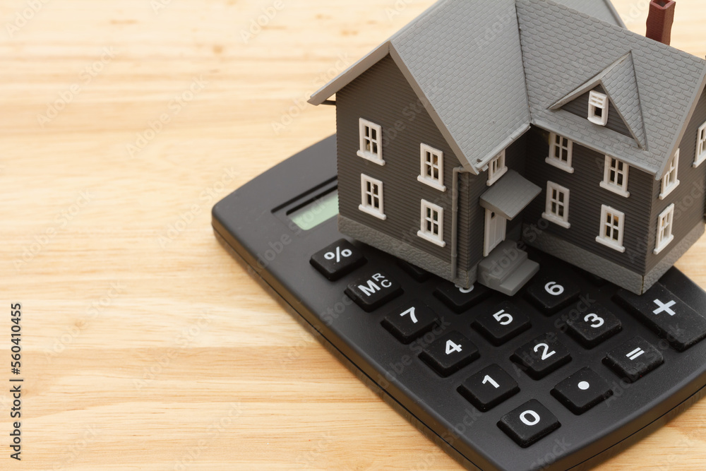 Mortgage calculator with a house on a wood desk Mortgage calculator with a house on a wood desk