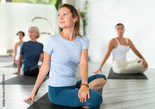 Portrait of sporty women practicing Matsyendrasana known as Lord of Fishes Pose during group yoga training