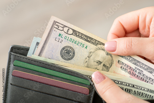 American fifty dollar banknote and grey wallet in female hands, close up. Finances, US money, world currency and business concept