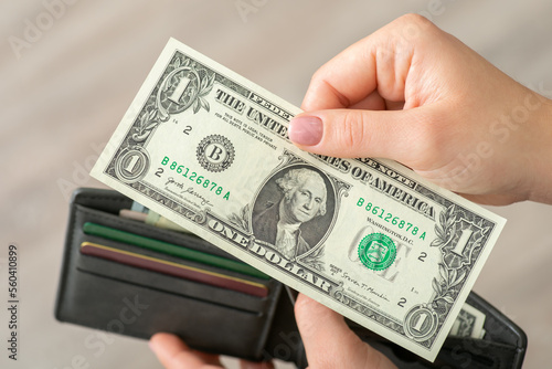 One dollar in female hand, close up. American money, cash, world currency, banknotes of small nominal, concept of making purchases and paying for goods