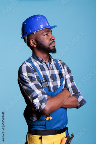 African american builder detailing the work he has just completed on the installation of electrical wiring to light the roof. Electrician wearing coveralls hard hat in studio shot.