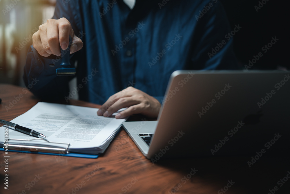 Man hand stamping approval signing on document or paperwork contract at desk. Man hand stamping approval signing on document or paperwork contract at desk.