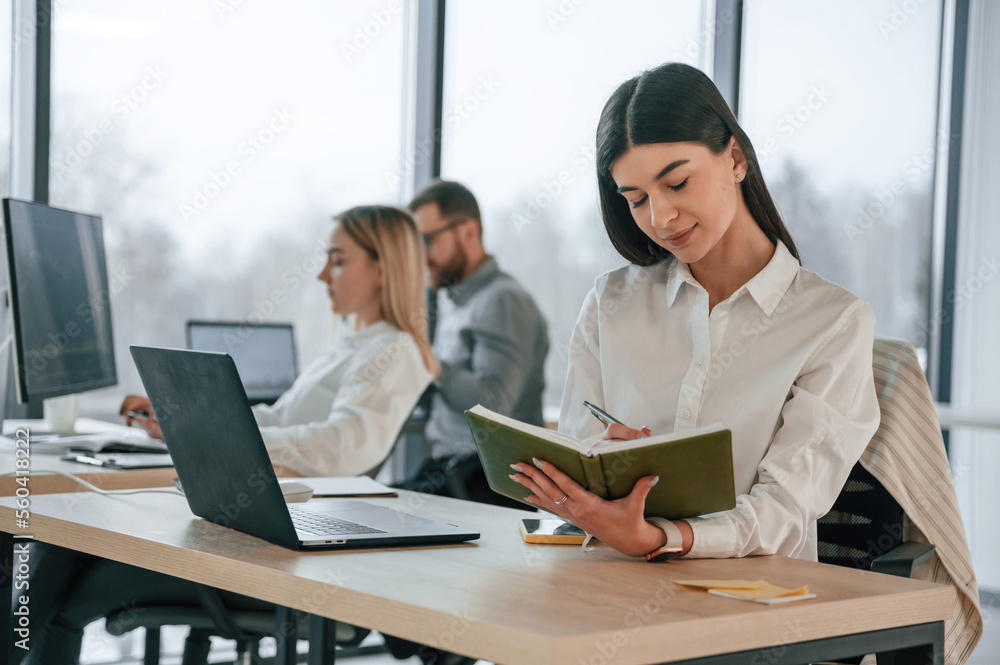 Woman is holding notepad. Successful team are working together in the office. Conception of business Woman is holding notepad. Successful team are working together in the office. Conception of business