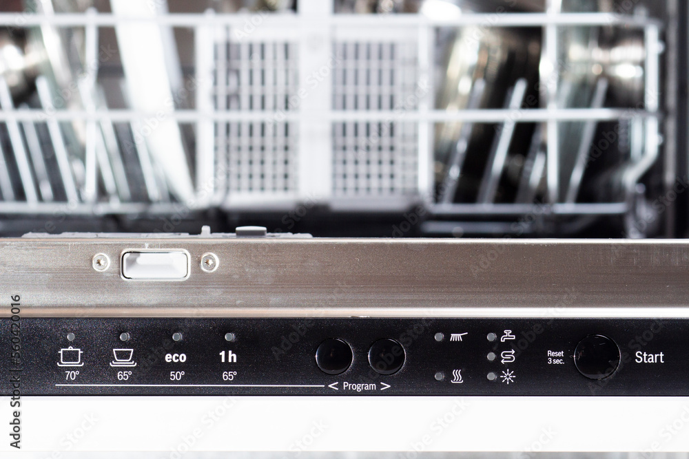 Control panel of dishwasher with various programmes. Opened dishwasher with dishes before washing.