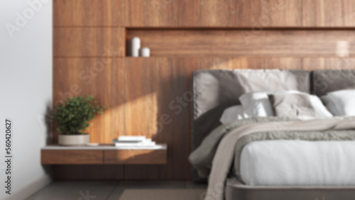 Blurred background, cozy bedroom close up. Wooden headboard. Velvet bed, bedding, pillows and carpet. Modern minimalist interior design