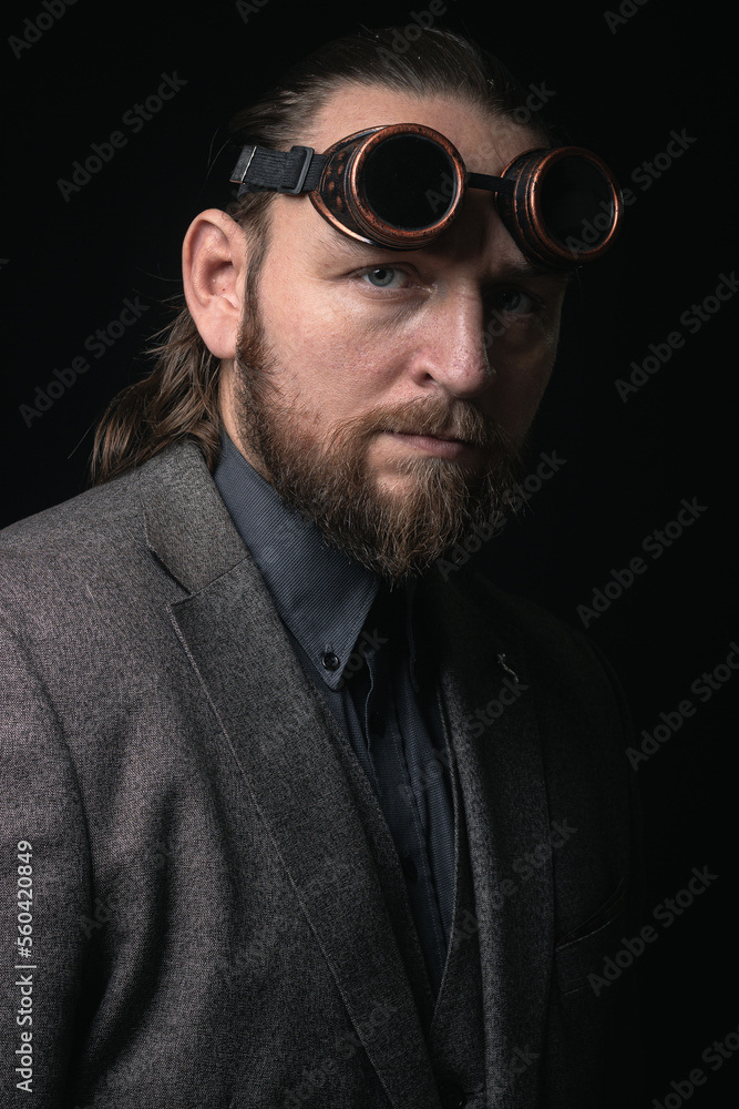 Fototapeta premium charismatic man in a classic suit and steampunk goggles on a black background stylish Portrait