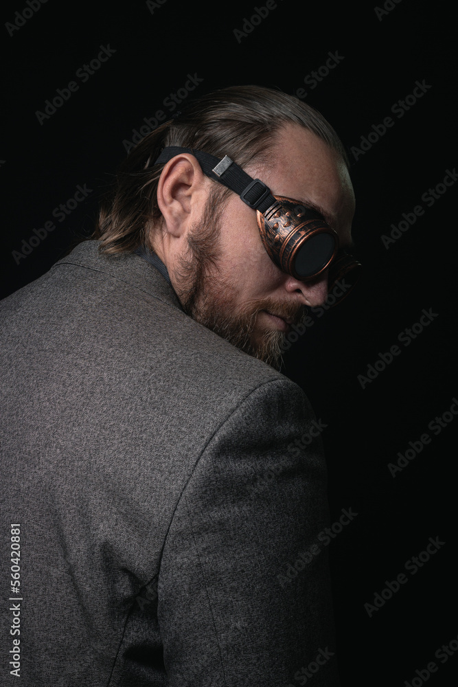 Fototapeta premium charismatic man in a classic suit and steampunk goggles on a black background stylish Portrait