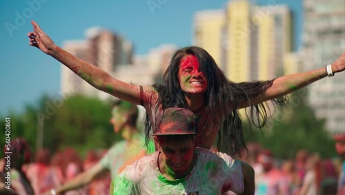 Portrait of a guy and a girl in the park with Holi colors, dancing and fun