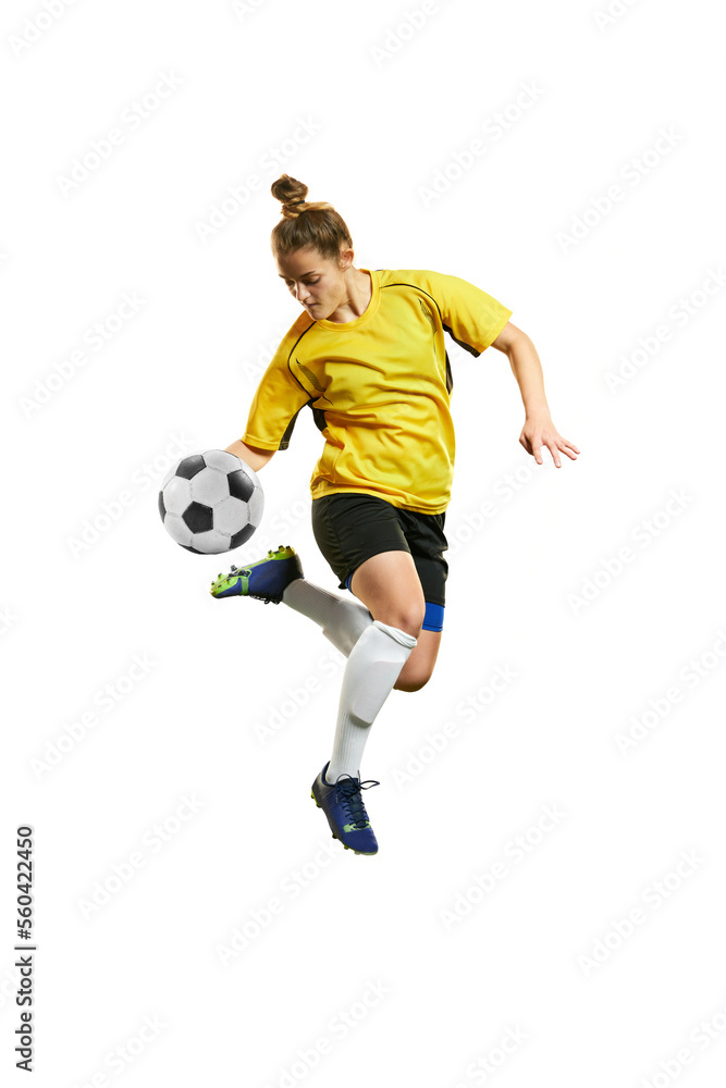 Young professional female football player in motion, playing football, soccer, hitting ball in a jump isolated over white background