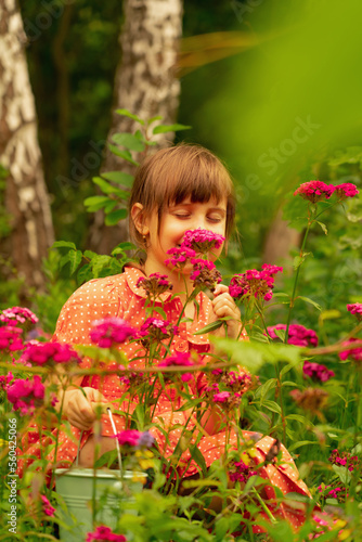 Charming cheerful young girl with colorful flowers. Wild nature and beauty concept.