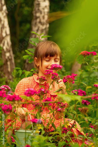 Portrait of charming cheerful young girl with colorful flowers. Wild nature and beauty concept.